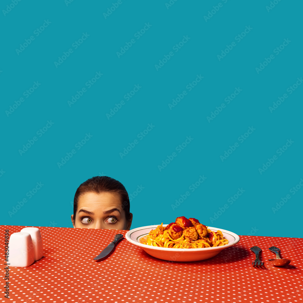 Wall mural Young girl spying on spaghetti with meatballs on plaid tablecloth isolated on bright blue background. Food pop art photography. Vintage, retro style interior