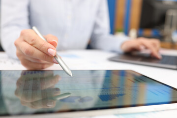 Fototapeta premium Female hand studying information on digital tablet with stylus closeup