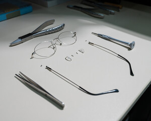 Disassembled glasses frame and tools. Optics work table.
