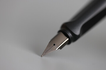 Closeup of metal ink pen head on gray background