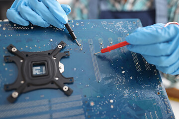 Repairman diagnosing breakdown in computer motherboard using tester closeup