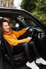 Fototapeta na wymiar Portrait of young beautiful woman in yellow sweater sitting in the car.