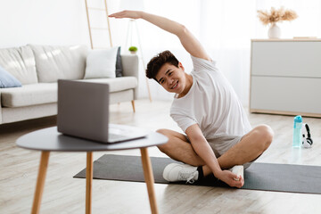 Asian guy doing stretching exercise watching online tutorial