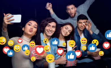 Cheerful young multiracial friends at party or theater with popcorn take selfie on smartphone