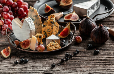 Various kind of cheese, traditional pieces of french, italy and spanish manchego cheese with grapes and figs served on wooden table
