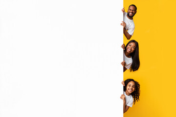 Black people peeking out blank white advertising billboard at studio