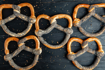Fresh prepared homemade soft pretzels. Different types of baked bagels with seeds on a black background.