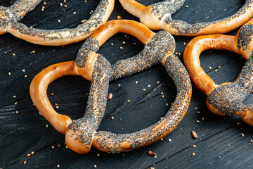 Fresh prepared homemade soft pretzels. Different types of baked bagels with seeds on a black background.