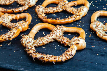 Fresh prepared homemade soft pretzels. Different types of baked bagels with seeds on a black background.