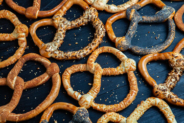 Fresh prepared homemade soft pretzels. Different types of baked bagels with seeds on a black background.