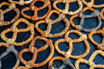 Fresh prepared homemade soft pretzels. Different types of baked bagels with seeds on a black background.