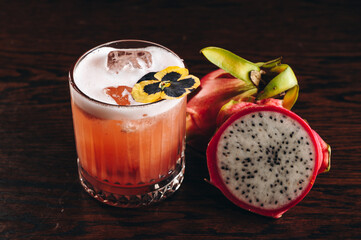 Glass of dragonfruit refresher drink on table with ice cubes. Pitahaya fruits