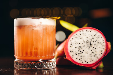 Glass of dragonfruit refresher drink on table with ice cubes. Pitahaya fruits