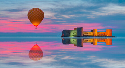 Hot air balloon flying over the maiden's castle (Kiz Kalesi) at twilight blue hour - Mersin, Turkey