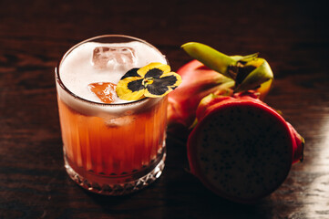 Glass of dragonfruit refresher drink on table with ice cubes. Pitahaya fruits