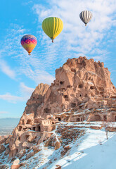 Fototapeta na wymiar Hot air balloon flying over spectacular Cappadocia, Uchisar castle in the background - Goreme, Turkey