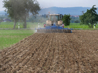 On a field in Wennerode am Harz in the state of Lower Saxony, a tractor is cultivating heavy Harz...
