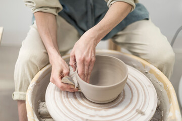 Female ceramic artist in apron working in pottery workshop