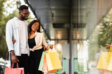 Black woman hugging man pointing at mall window