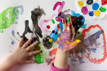Girl at school painting with finger paints. Lots of colors and lots of fun. Girl's hands stained...
