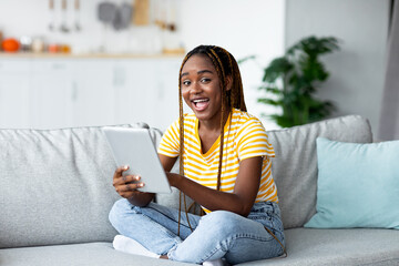 Obraz premium Smiling black woman trader working on pad from home