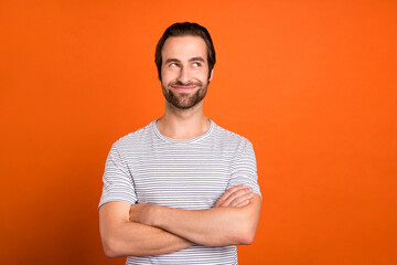 Photo of young man crossed hands wondered plan thoughtful look empty space isolated over orange color background