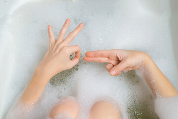 Female masturbation, bathroom sex concept. Female hands in a bath with foam depict erotic gestures. Sexual gratification in the bath.