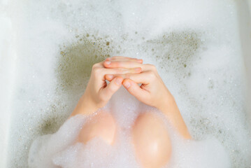 Relaxation, reflection, thoughtfulness in a bubble bath concept. Women's hands in foam.