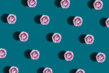Decorative spring pattern made of pink paper rose flowers on dark cyan background. Nature flat lay....