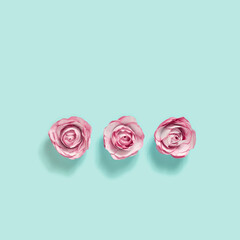 Minimal arrangement made of three paper pink roses on bright green background. Nature concept art. Flat lay. Valentine and spring visual.