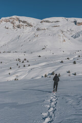 An unrecognizable male hiker wearing snowshoes walking in the French Alps on a cold winter day...
