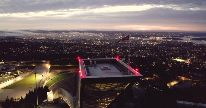 Flag Waving In The Wind At The Tower Of Holmenkollbakken At Night In Oslo, Norway. - aerial