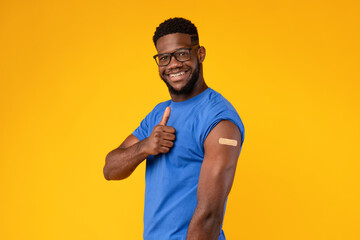 Vaccinated African American Man Gesturing Thumbs-Up Approving Vaccine, Yellow Background