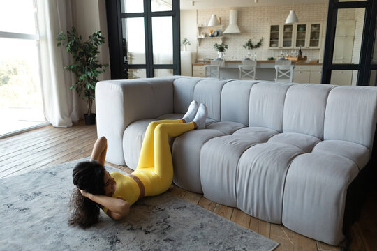 Full length of young woman working out in her home gym, doing abs exercises during coronavirus quarantine, copy space