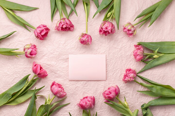 Frame of tulips laid out in the shape of a heart on a pale pink background and an empty postcard with a place for the text of congratulations on Valentine's Day, mother's day or birthday.