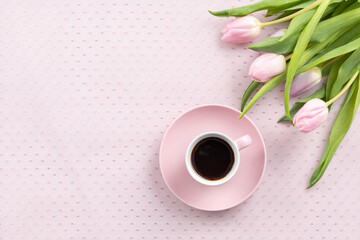 Spring background with flowers, a cup of coffee and a bouquet of pink tulips on a delicate lace tablecloth for a good morning on March 8 or Mother's Day with a place for text.