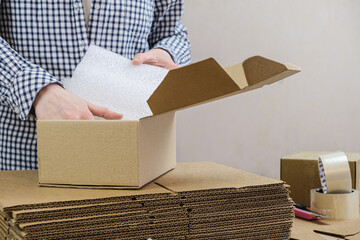 Warehouse employee packs the order of the online store in a cardboard box