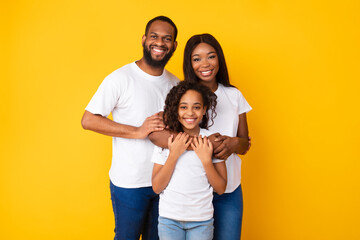 Happy black husband posing with wife and smiling daughter