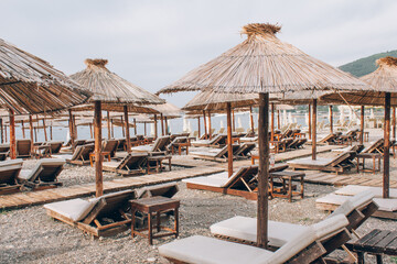 Sea beach with sunbeds and beach umbrellas in Budva, view from Adriatic sea coast, summer tourist season, empty sea beach without tourists