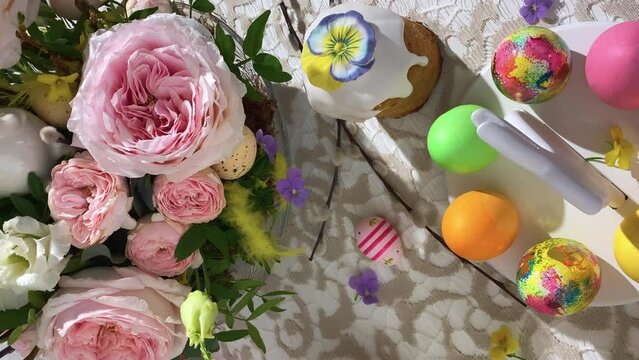 Vertical view. Festive Easter table setting. Easter cake, Easter Eggs, Flower arrangements and home decorations for holiday.Slow motion