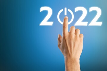 hand presses the start button for 2022. Happy New Year resolution, change, goal, vision,