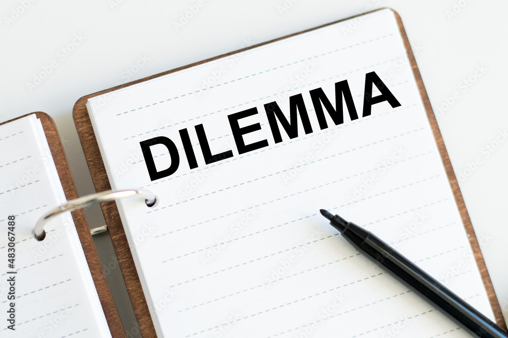Poster text dilemma on an open notepad on a table next to a black marker, a business concept