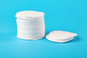A stack of white cotton pads close-up on a blue background. Skin cleaning.