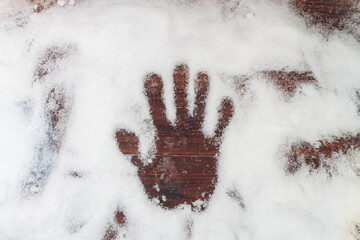 Handprint of a man in the snow on a wooden brown background