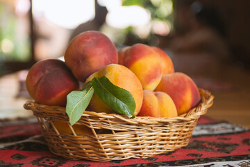 Fresh peaches fruits with leaves in basket on rustic background