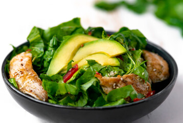 chicken salad with avocado in a black bowl. Healthy food