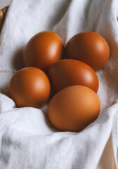 chicken eggs in a wicker basket covered with a linen towel are