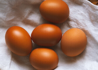 chicken eggs in a wicker basket covered with a linen towel are