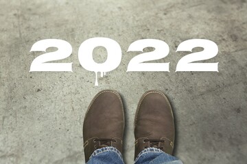 Top view of man feet standing on cement floor and 2022 text, Happy new year concept.