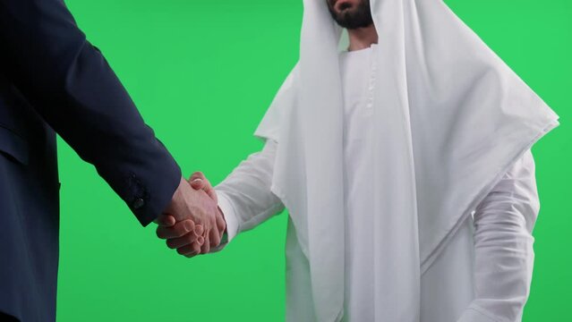 Chromakey template, Arab man in a white kandura makes a good deal with a partner buisnessman in a suit, a handshake between two buisnessman.